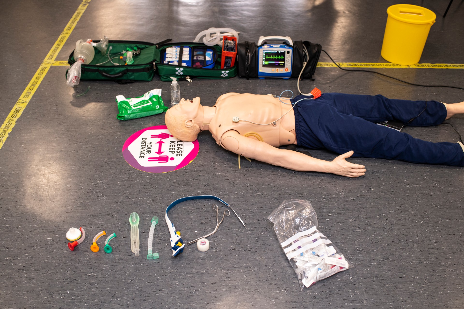 Manikin with a paramedic bag and breathing support equipment laid out beside it.
