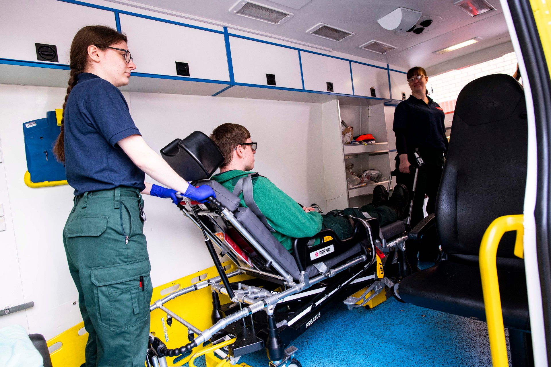 A student helping to remove a patient (played by an actor) from an ambulance on a trolley.