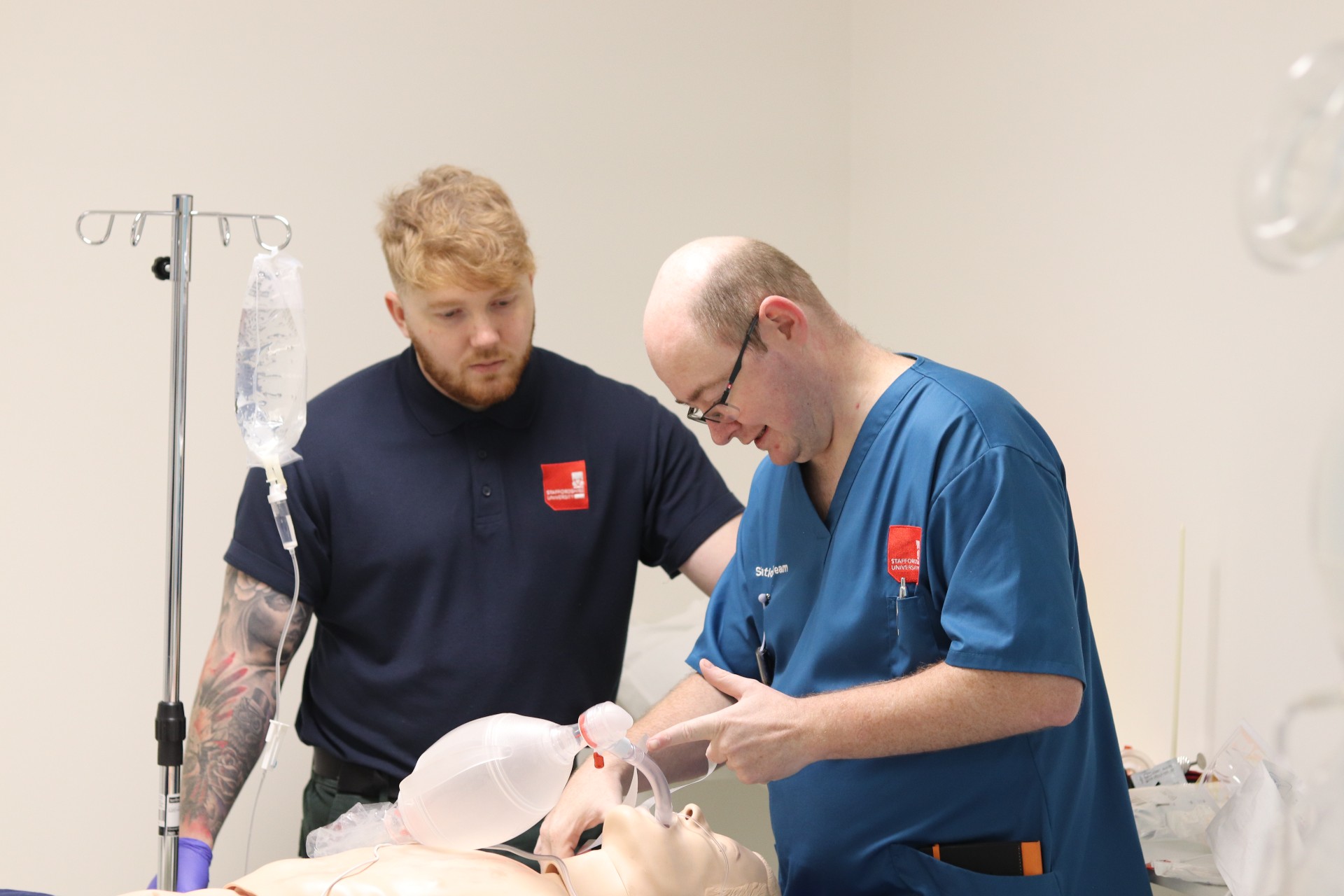 A simulation practitioner supports a student carrying out airway management.